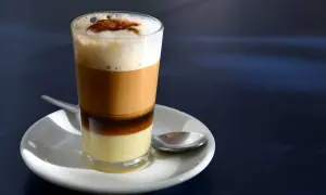 Ein geschichteter Kaffee mit Kondensmilch, Espresso und Milchschaum, bestreut mit Zimt. Ein süßer Genuss, wie ein flüssiger bonbon kaffee.