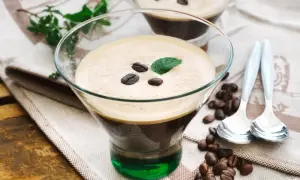 Ein köstlicher Eiskaffee italienisch, garniert mit Kaffeebohnen und Minze, serviert in einem Glas mit grüner Likörschicht.