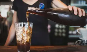 Eine Person gießt Cold Brew Kaffee mit Eis in ein Glas. Cold Brew ist ein Kaffee, der kalt extrahiert wird.