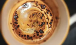Nahaufnahme einer Tasse Kaffee mit Crema und Kaffeepulver, die an die Herstellung von Instantkaffee erinnert.