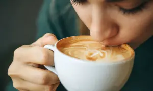 Eine Person trinkt genussvoll einen Latte Macchiato. Der warme Kaffee könnte ein kleiner Trost bei Gefühlen der Depression sein.