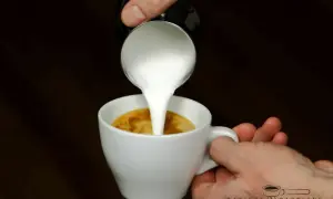 Milch wird in einen Espresso gegossen, um einen perfekten Espresso macchiato zu kreieren.