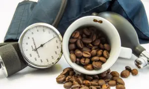 Blutdruckmessgerät und Kaffeebohnen. Die Frage, ob Kaffee senkt den Blutdruck, wird hier visuell thematisiert.
