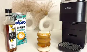 Ein leckerer Kokosnuss-Latte mit Alpro Barista Coconut, Vanillesirup und einer Kaffeemaschine.