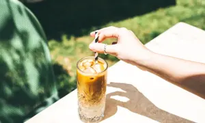 Erfrischender Eiskaffee ohne Eis, mit einem gestreiften Strohhalm, der in einem Glas mit Eiswürfeln steckt.