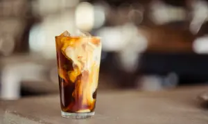 Ein Glas mit Eiswürfeln und cremiger Milch, die sich in dunklem Kaffee wirbelt. Perfekt für alle, die **cold brew selber machen** wollen.