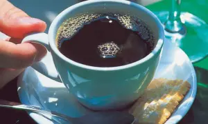 Eine Tasse schwarzer Kaffee mit Schaum, ein Keks und eine Löffel. So einfach ist, wie man schwarzen Kaffee macht.