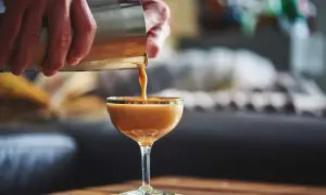 Ein cremiger Kaffee mit Alkohol wird aus einem Shaker in ein Glas gegossen. Ein köstlicher Kaffee-Cocktail, der zum Genießen einlädt.