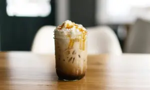 Ein köstlicher Caramel Frappuccino mit Sahne und Karamellsauce, serviert in einem Glas auf einem Holztisch.