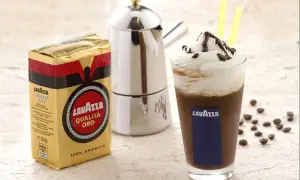 Ein köstlicher iced mocha mit Sahne und Schokoladensauce, daneben eine Packung Lavazza Qualità Oro Kaffee und eine Mokkakanne.