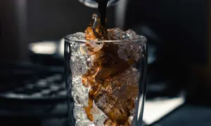 Heißer Espresso fließt auf Eiswürfel in einem Glas. Perfekt für ein erfrischendes iced americano rezept.