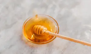Ein Honiglöffel in einer Schale mit flüssigem Honig, der an den süßen Geschmack von Honey Process Kaffee erinnert.
