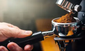 Frisch gemahlener Kaffee für den perfekten espresso geschmack. Eine Hand hält den Siebträger, während feines Kaffeepulver hineinfällt.