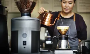 Barista bereitet mit einem Handfilter und einer Kupferkanne einen aromatischen Espresso zu.