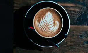 Ein Milchkaffee oder Cappuccino mit Latte Art auf einem Holztisch.