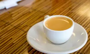 Eine Tasse Café Olé auf einem Unterteller, bereit zum Genuss auf einem Holztisch.