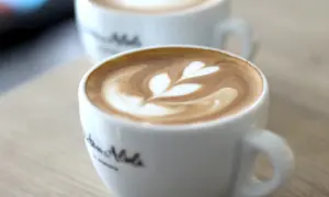 Zwei Tassen mit Latte Art, bereit zum Cappuccino trinken. Ein Herzmuster ziert den Schaum.