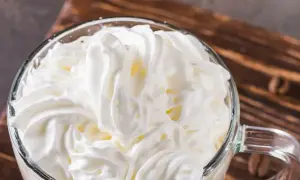 Ein Glas mit cremigem Cappuccino con panna, bedeckt mit einer üppigen Haube aus Schlagsahne.