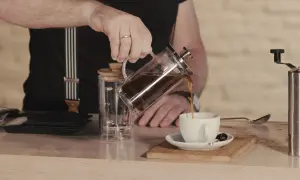 Mann gießt French Press Kaffee in eine Tasse. Die Menge ist für 2 Tassen ausgelegt.