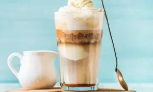 Ein cremiger Eiskaffee Karamell mit Sahnehaube, daneben ein Milchkännchen.