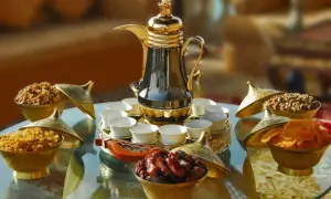 Elegante arabischer kaffee zubereitung mit Dallah, kleinen Tassen und Schalen voller Datteln, Nüssen und Trockenfrüchten.