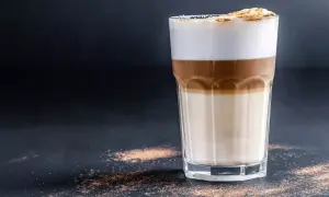 Ein Latte Macchiato mit drei Schichten: Milch, Espresso und Milchschaum, bestreut mit Zimt.