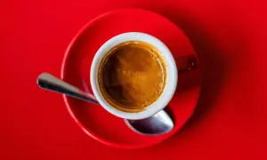 Eine Tasse Espresso auf rotem Untergrund. Die Wirkung von Espresso auf den Schlaf ist oft belebend, nicht schlaffördernd.