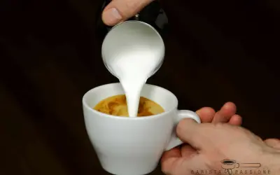 Milch wird in einen Espresso gegossen, um einen perfekten Espresso macchiato zu kreieren.