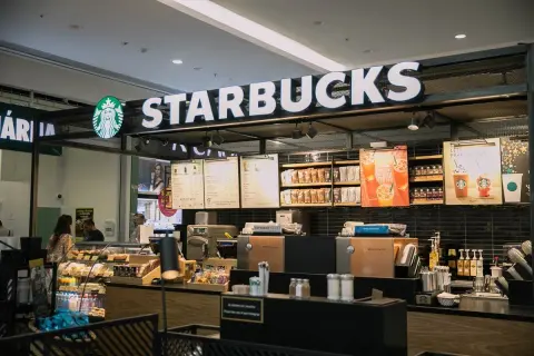 Starbucks-Theke mit leuchtendem Logo, Menütafeln und Auslagen, die die lange Starbucks-Geschichte und Kaffeekultur widerspiegeln.