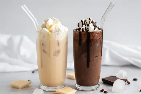 Zwei eisgekühlte Getränke, ein heller und ein dunkler, mit Sahne und Schokoladensauce. Perfekt für Caffè Mocha Rezepte.