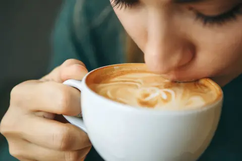 Eine Person trinkt genussvoll einen Latte Macchiato. Der warme Kaffee könnte ein kleiner Trost bei Gefühlen der Depression sein.