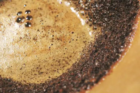 Nahaufnahme von frisch gebrühtem Filterkaffee mit cremigem Schaum und Kaffeesatz. So entsteht der köstliche Geschmack von Filterkaffee.