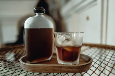 Kühl und erfrischend: Ein Glas Cold Brew mit Eiswürfeln neben einer Karaffe. Wie lange ziehen lassen für perfekten Geschmack?