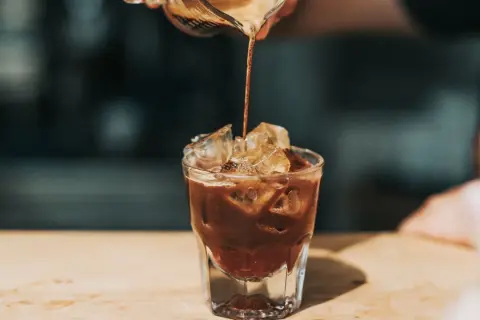 Ein Espresso wird in ein Glas mit Eis gegossen. Ist kalter Kaffee gesund? Diese erfrischende Zubereitung könnte die Antwort sein.