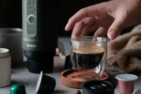 Ein Mann bereitet mit einem Outin-Gerät einen Espresso zu. Er verwendet eine Kapsel und kaltes Wasser für den perfekten instant kaffee.