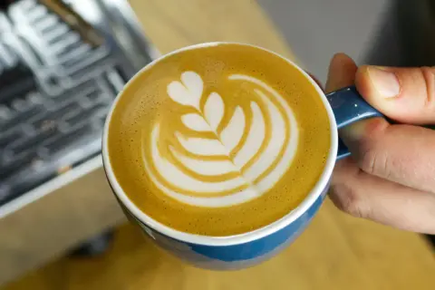 Eine Tasse Milchkaffee mit Latte Art, die das Ergebnis einer perfekten Milchkaffee Zubereitung zeigt.