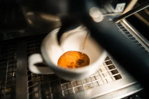 Frisch gebrühter Espresso fließt in eine weiße Tasse. Manche sagen, entkoffeinierter Kaffee sei ungesund, aber dieser hier sieht köstlich aus.