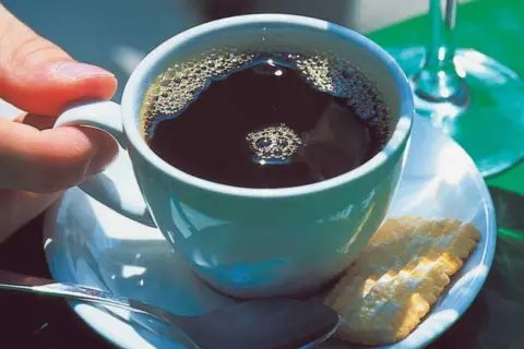 Eine Tasse schwarzer Kaffee mit Schaum, ein Keks und eine Löffel. So einfach ist, wie man schwarzen Kaffee macht.