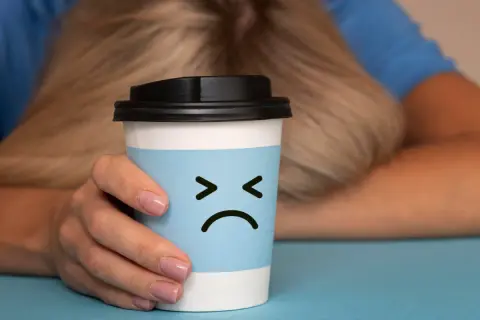 Trauriger Kaffeebecher mit traurigem Gesicht, der die Nachteile von Kaffee symbolisiert.