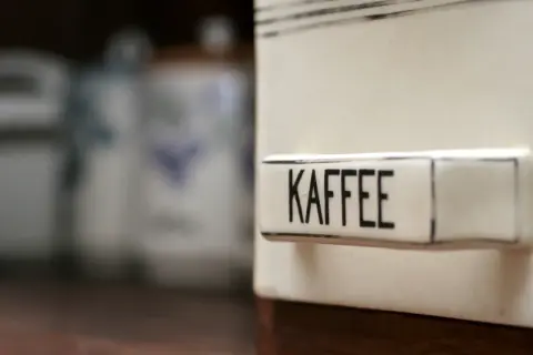 Ein Behälter mit der Aufschrift "KAFFEE" steht im Vordergrund. Im Hintergrund sind weitere Vorratsdosen zu sehen. Man fragt sich, ob Kaffee schlecht werden kann.