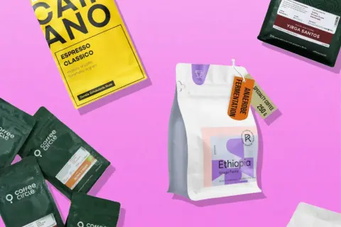 Verschiedene Kaffeepackungen, die die Vielfalt des coffee origin zeigen. Eine gelbe Packung "Caimano Espresso Classico", grüne Packungen von "Coffee Circle" und eine weiße Packung "Ethiopia Uraga Funky".