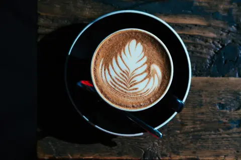 Ein Milchkaffee oder Cappuccino mit Latte Art auf einem Holztisch.