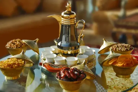 Elegante arabischer kaffee zubereitung mit Dallah, kleinen Tassen und Schalen voller Datteln, Nüssen und Trockenfrüchten.