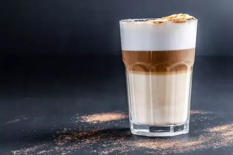 Ein Latte Macchiato mit drei Schichten: Milch, Espresso und Milchschaum, bestreut mit Zimt.