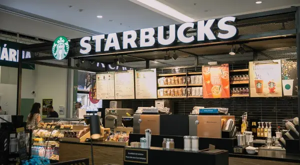 Starbucks-Theke mit leuchtendem Logo, Menütafeln und Auslagen, die die lange Starbucks-Geschichte und Kaffeekultur widerspiegeln.