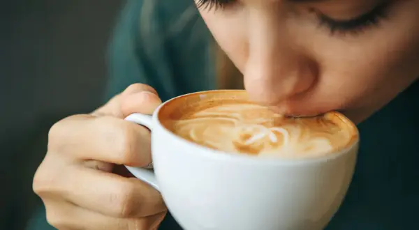 Eine Person trinkt genussvoll einen Latte Macchiato. Der warme Kaffee könnte ein kleiner Trost bei Gefühlen der Depression sein.
