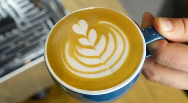 Eine Tasse Milchkaffee mit Latte Art, die das Ergebnis einer perfekten Milchkaffee Zubereitung zeigt.