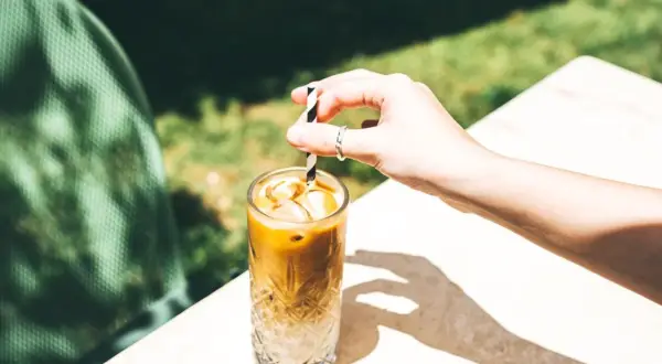 Erfrischender Eiskaffee ohne Eis, mit einem gestreiften Strohhalm, der in einem Glas mit Eiswürfeln steckt.