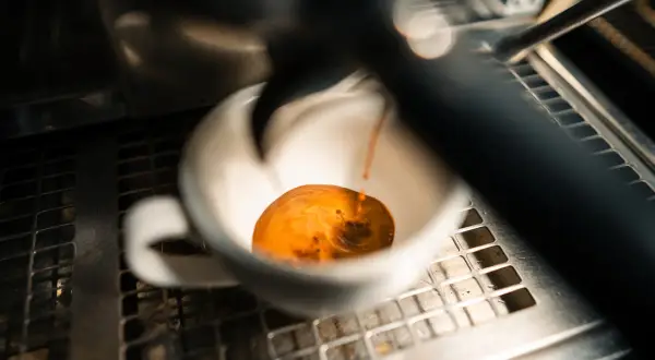 Frisch gebrühter Espresso fließt in eine weiße Tasse. Manche sagen, entkoffeinierter Kaffee sei ungesund, aber dieser hier sieht köstlich aus.