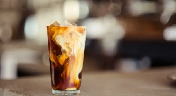Ein Glas mit Eiswürfeln und cremiger Milch, die sich in dunklem Kaffee wirbelt. Perfekt für alle, die **cold brew selber machen** wollen.